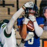 GVSU football player makes a catch while a defender tries to knock the ball away.